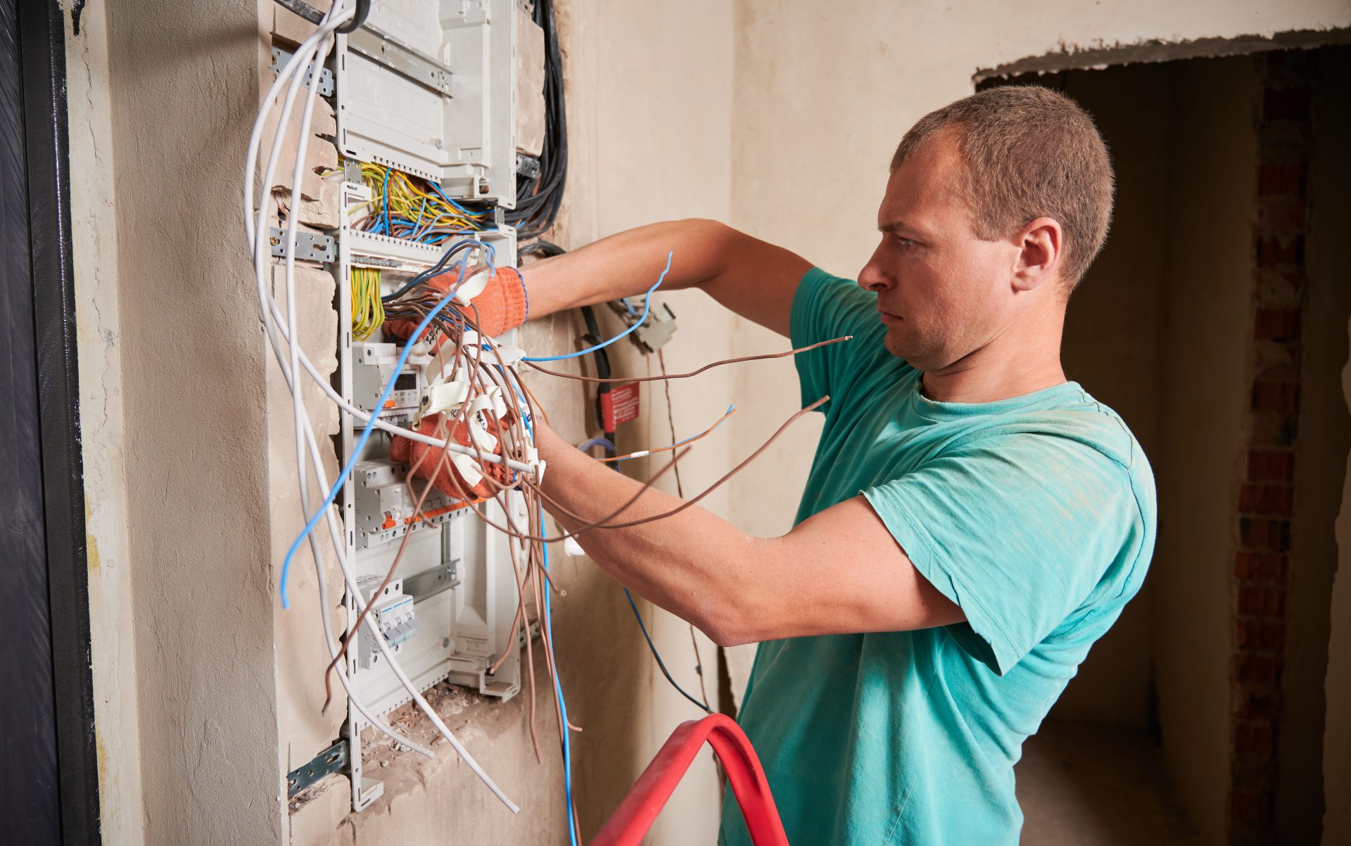 Male electrician repairing electrical control panel at home.